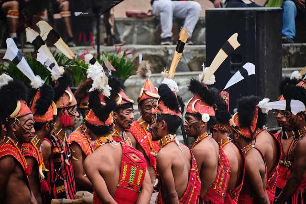 Konyak men striking a traditional log drum during the Aoling Festival, creating rhythmic beats as part of the celebration.