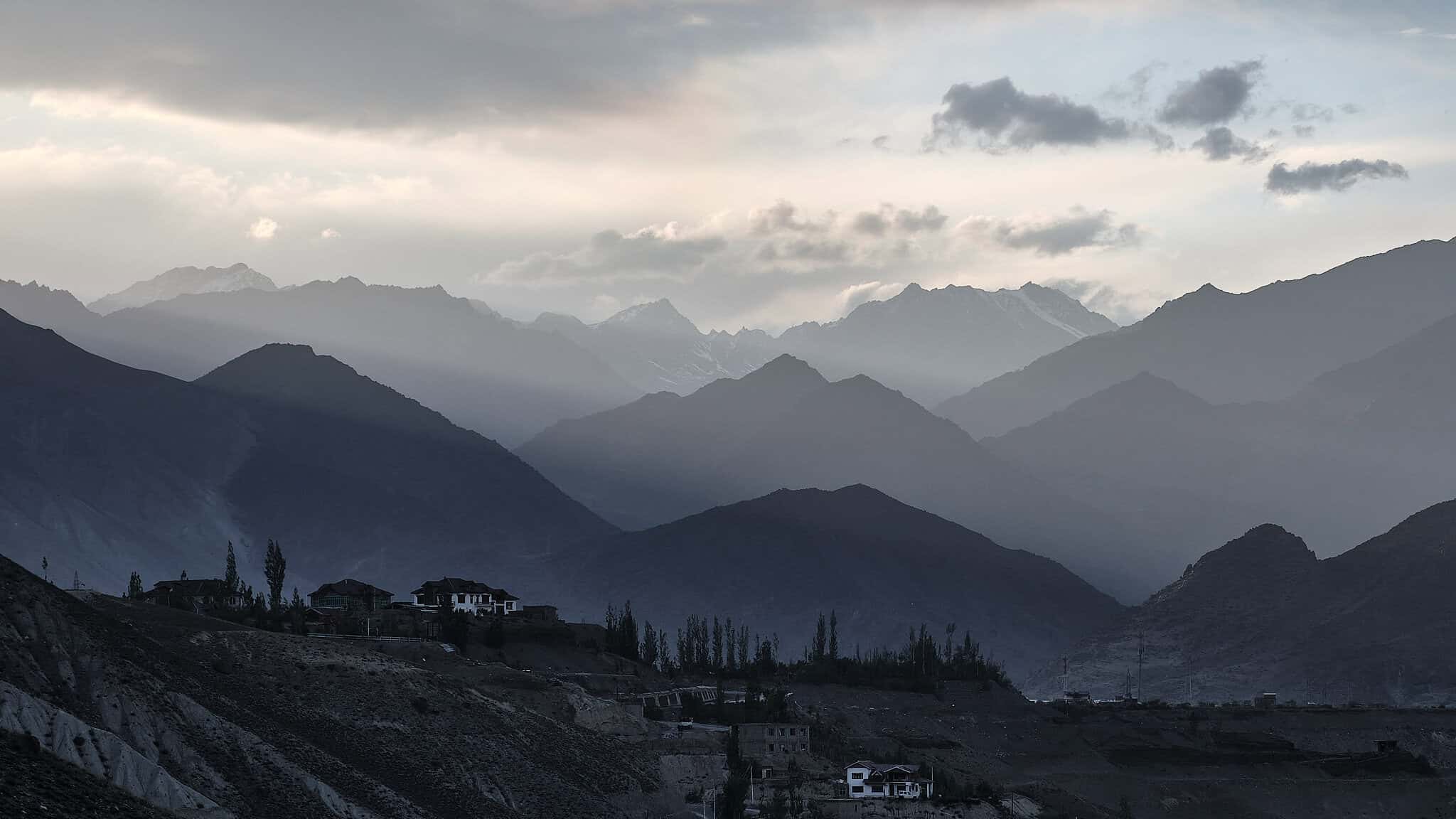 Hazy layers of mountains fading into the distance, with tiny scattered houses providing a sense of scale against the vast landscape.