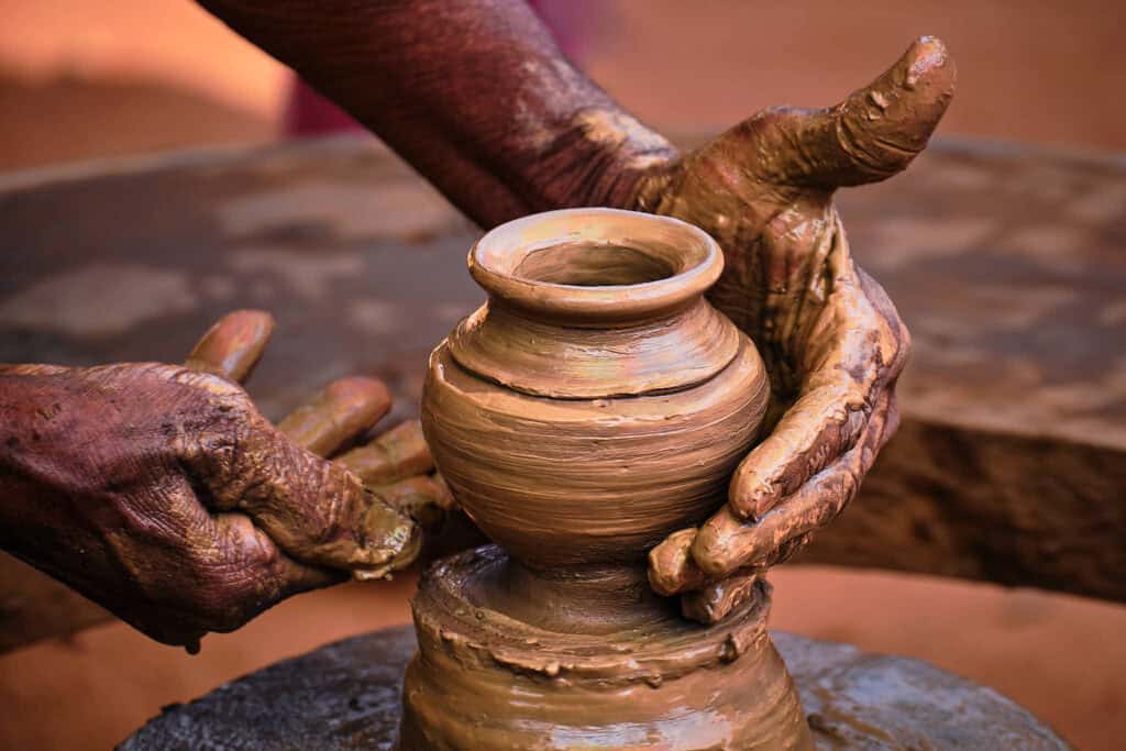 Close-up of a potter’s hands shaping a clay pot on a spinning wheel as it gradually takes form.