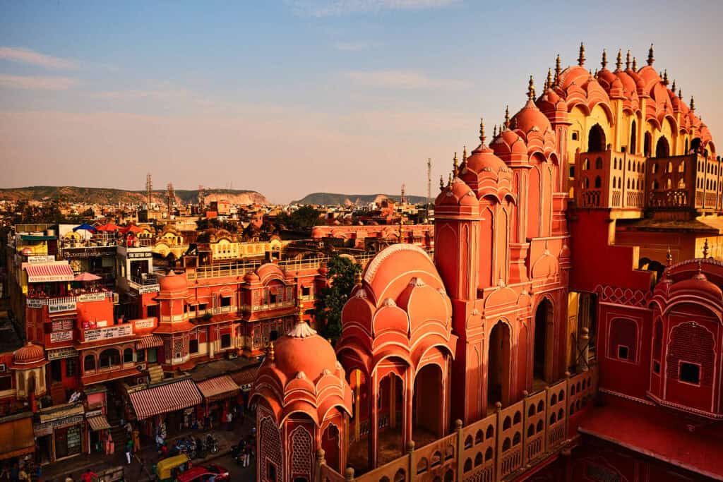 Hawa Mahal glowing in warm orange hues at sunset, its façade lit by the fading light in Rajasthan.