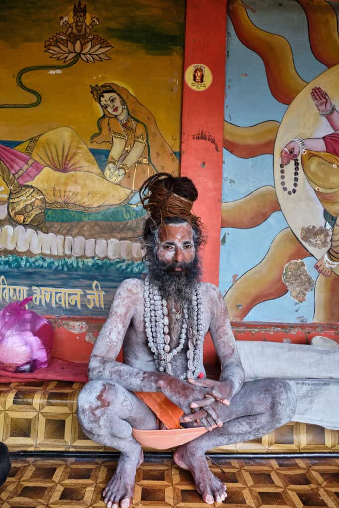 Sadhu in Varanasi dressed in vibrant traditional attire, seated in a contemplative pose.