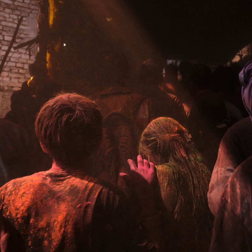 People returning home after Holi celebrations, with traces of color on their clothes and skin.